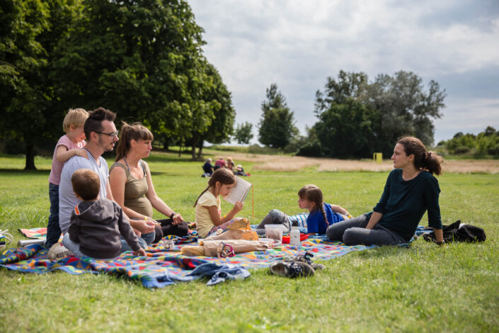 Familie beim Picknick in der Sonne auf der Wiese im Park in Liebenberg.
