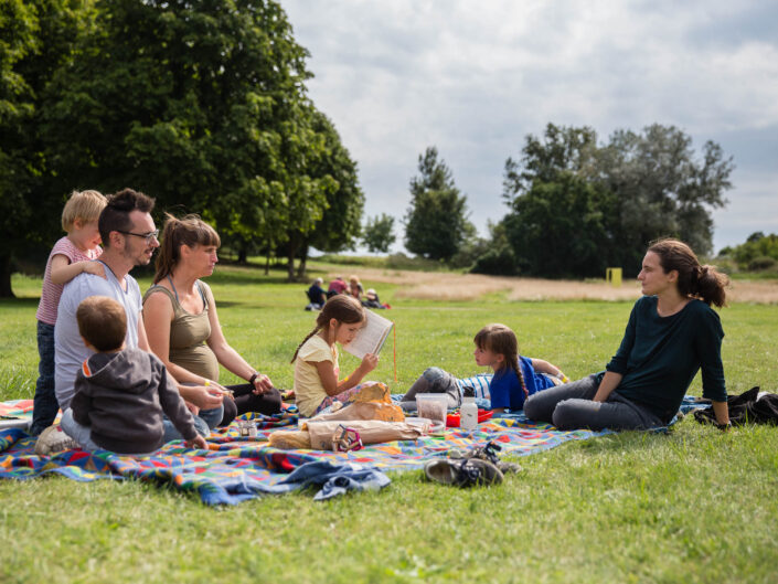Familie beim Picknick in der Sonne auf der Wiese im Park in Liebenberg.