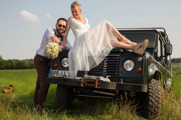 Brautpaar posiert am Auto Land Rover